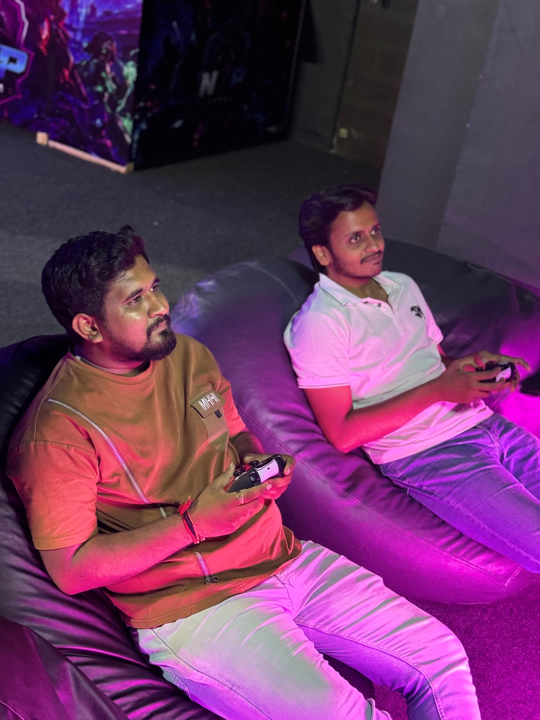 Two players on bean bags with controllers in pink light