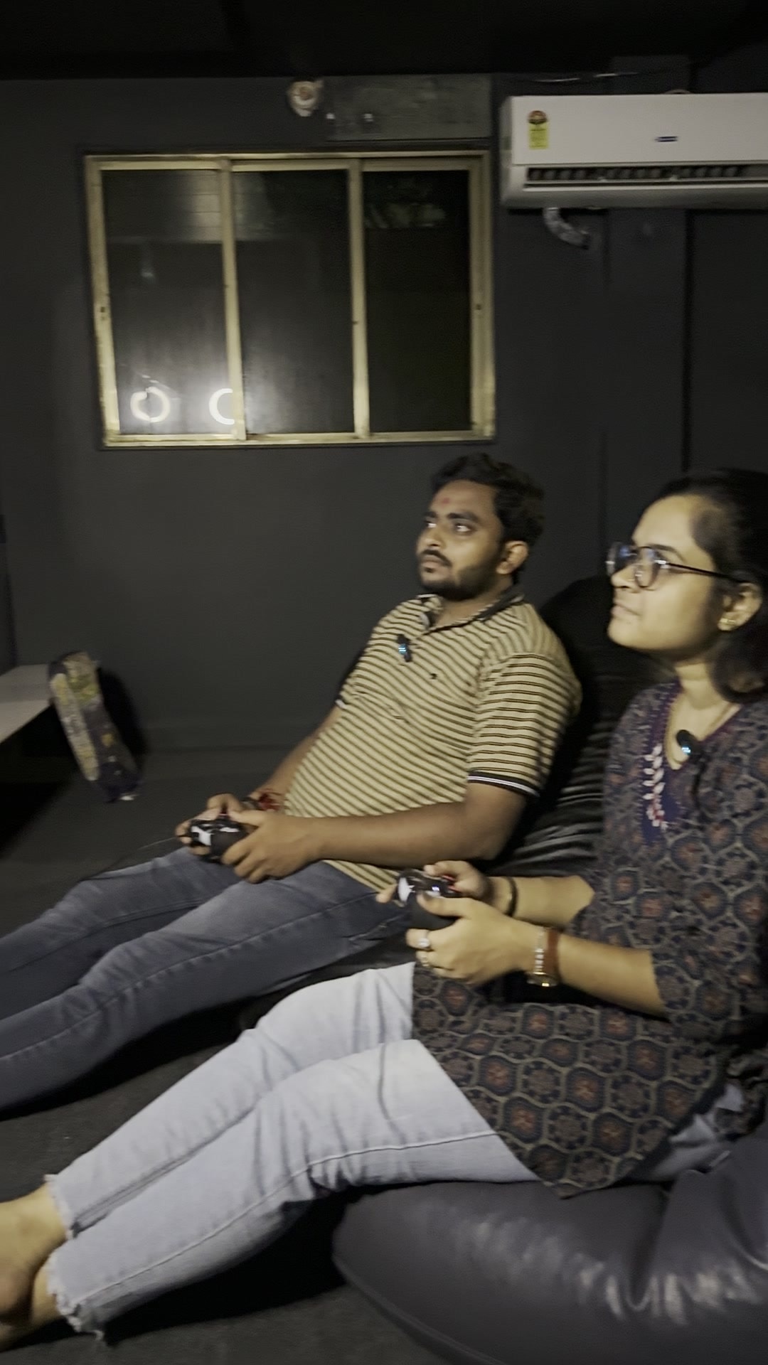 Two players side by side with PS5 controllers, eyes on the TV