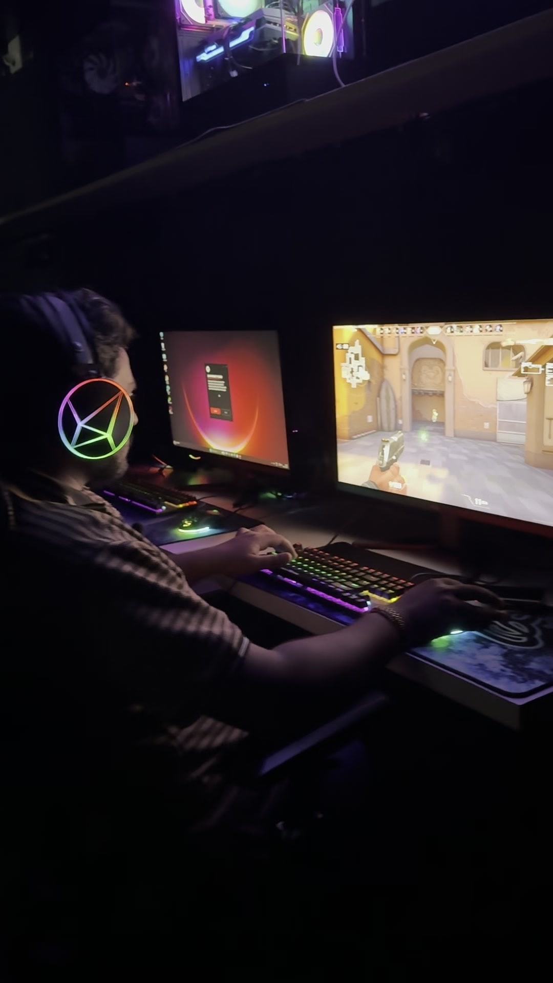 A player at a dual-monitor gaming PC with an RGB keyboard