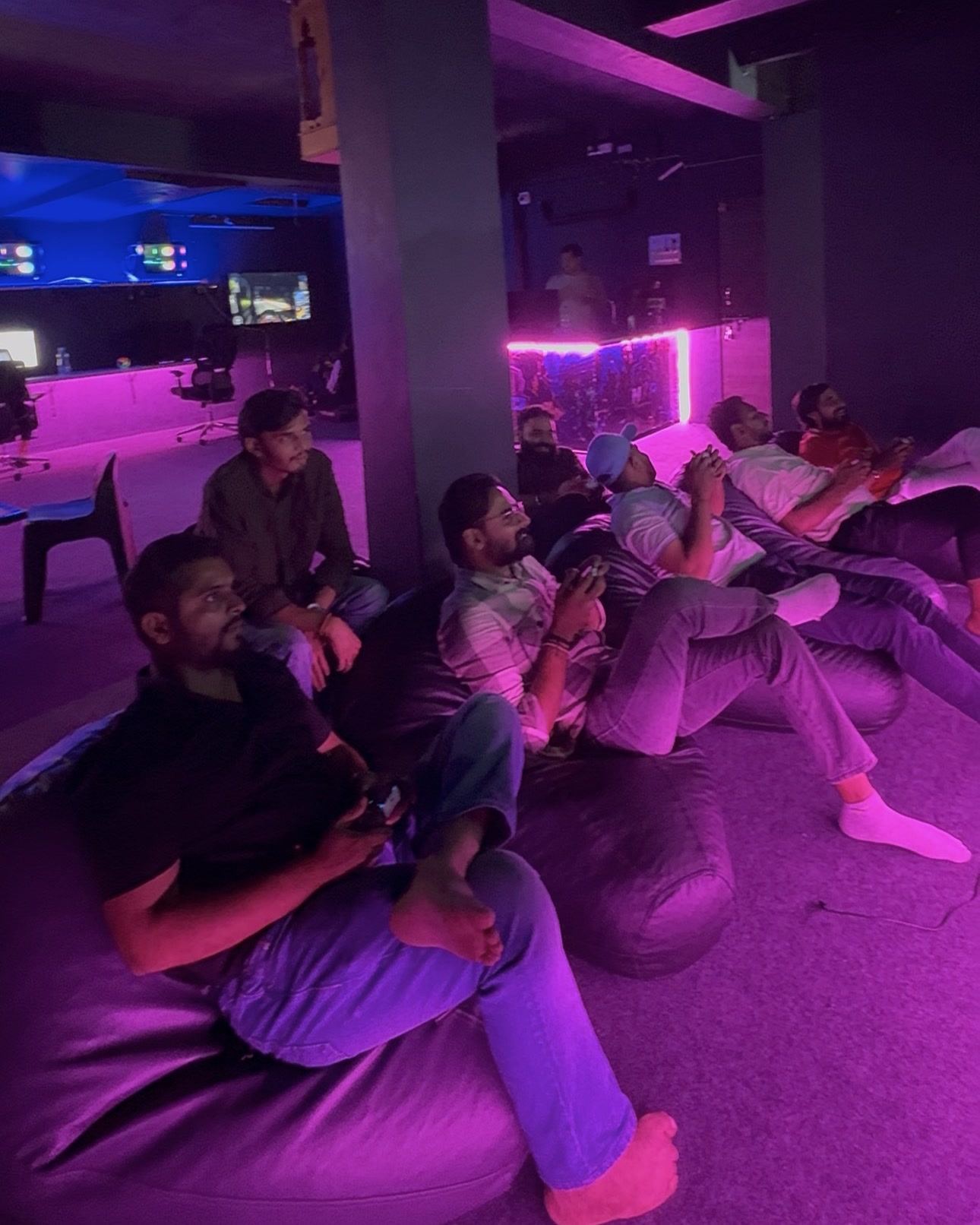 A group on bean bags with PS5 controllers under pink light at N2P Arena