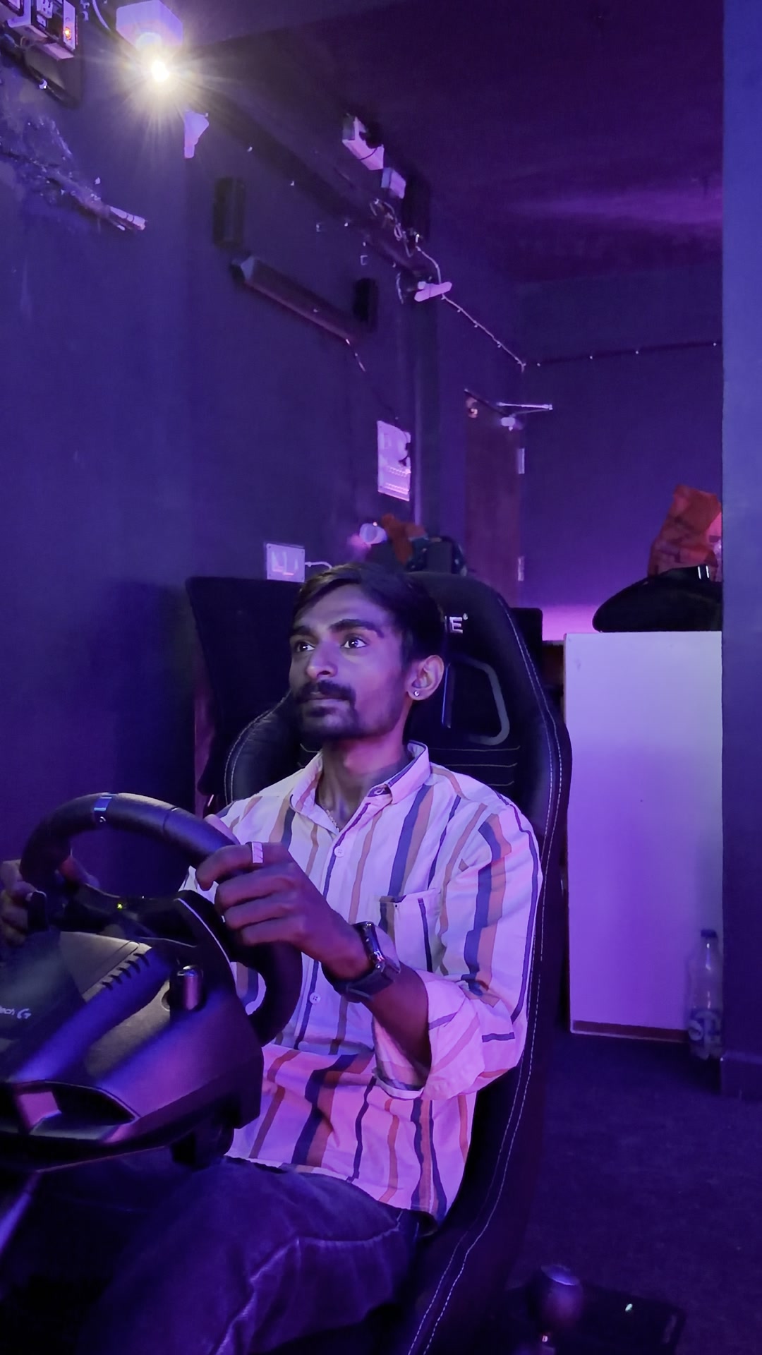 A player in the racing simulator seat with hands on the wheel
