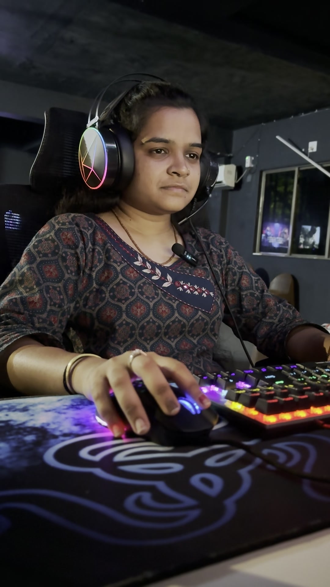 A player in an RGB headset with a hand on the mouse above a glowing keyboard