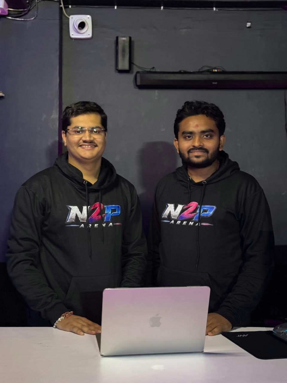 Priyanshu and Harsh behind a laptop at the N2P Arena counter, both in N2P Arena hoodies